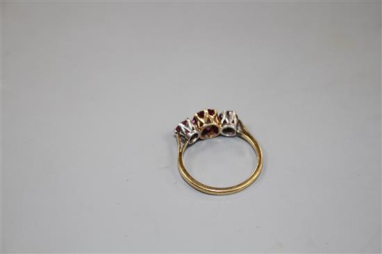 An 18ct and three stone ruby and garnet?? set dress ring, size M, gross 2.7 grams.